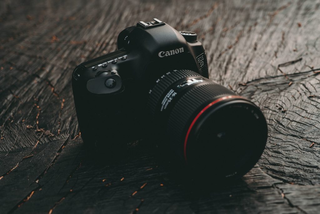 A canon camera on a wooden table.