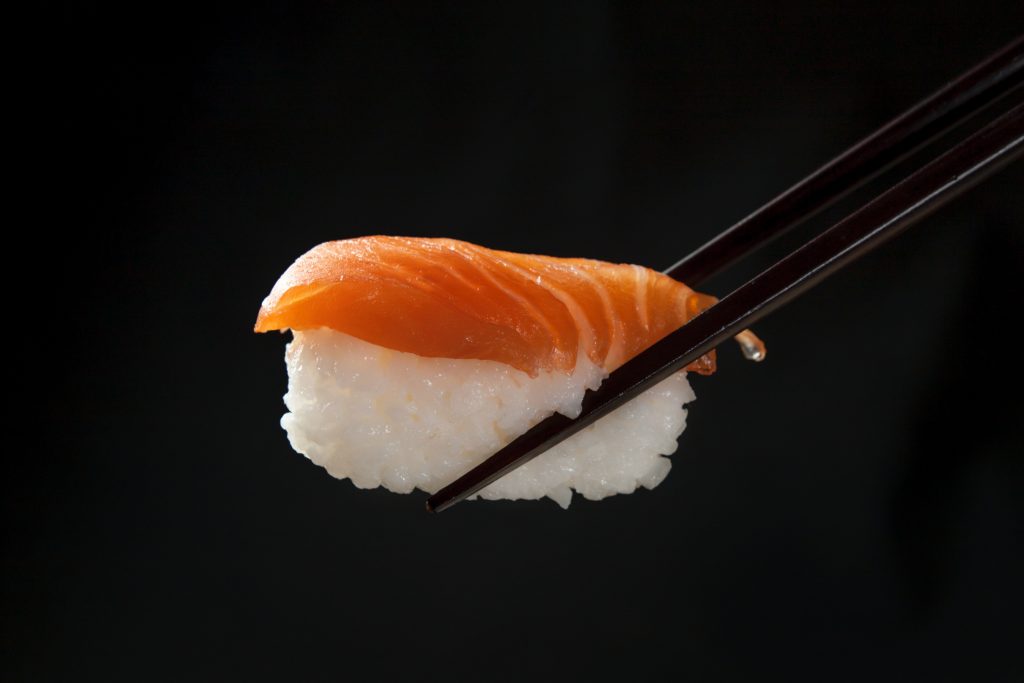 Sushi being held by chopstick.