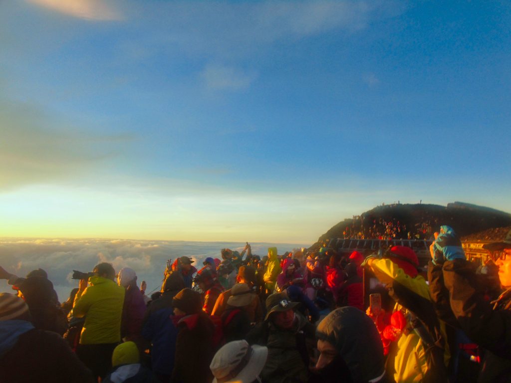 Hikers onlooking the sunrise at the summit of Mt. Fuji.