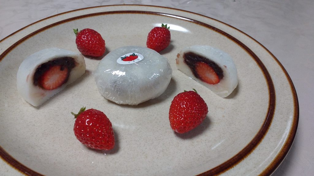 A p;ate of daifuku cut in half with strawberries and anko filling 