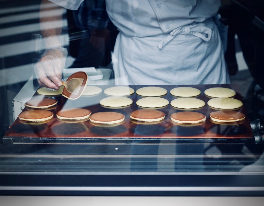 A chef making dorayaki on hot plate.