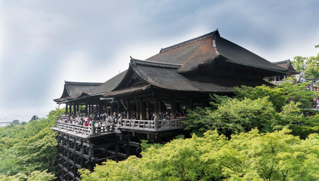 A picture of the Kiyomizu temple surrounded by green summer trees. 