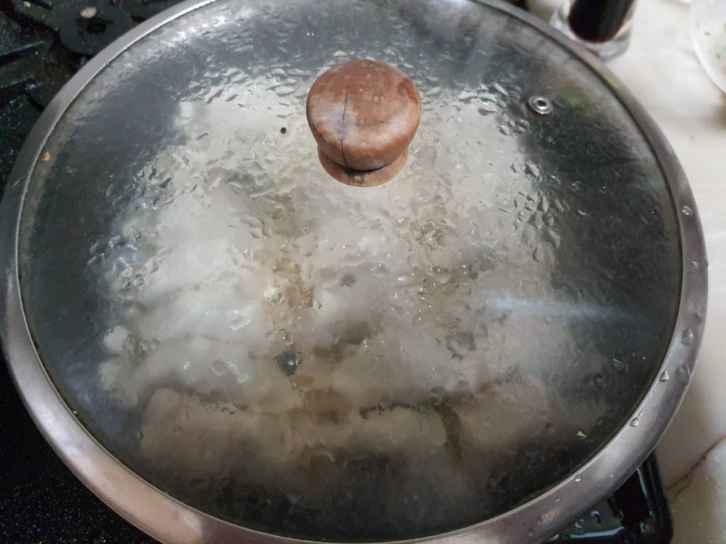 The Gyoza cooking inside a covered frying pan.